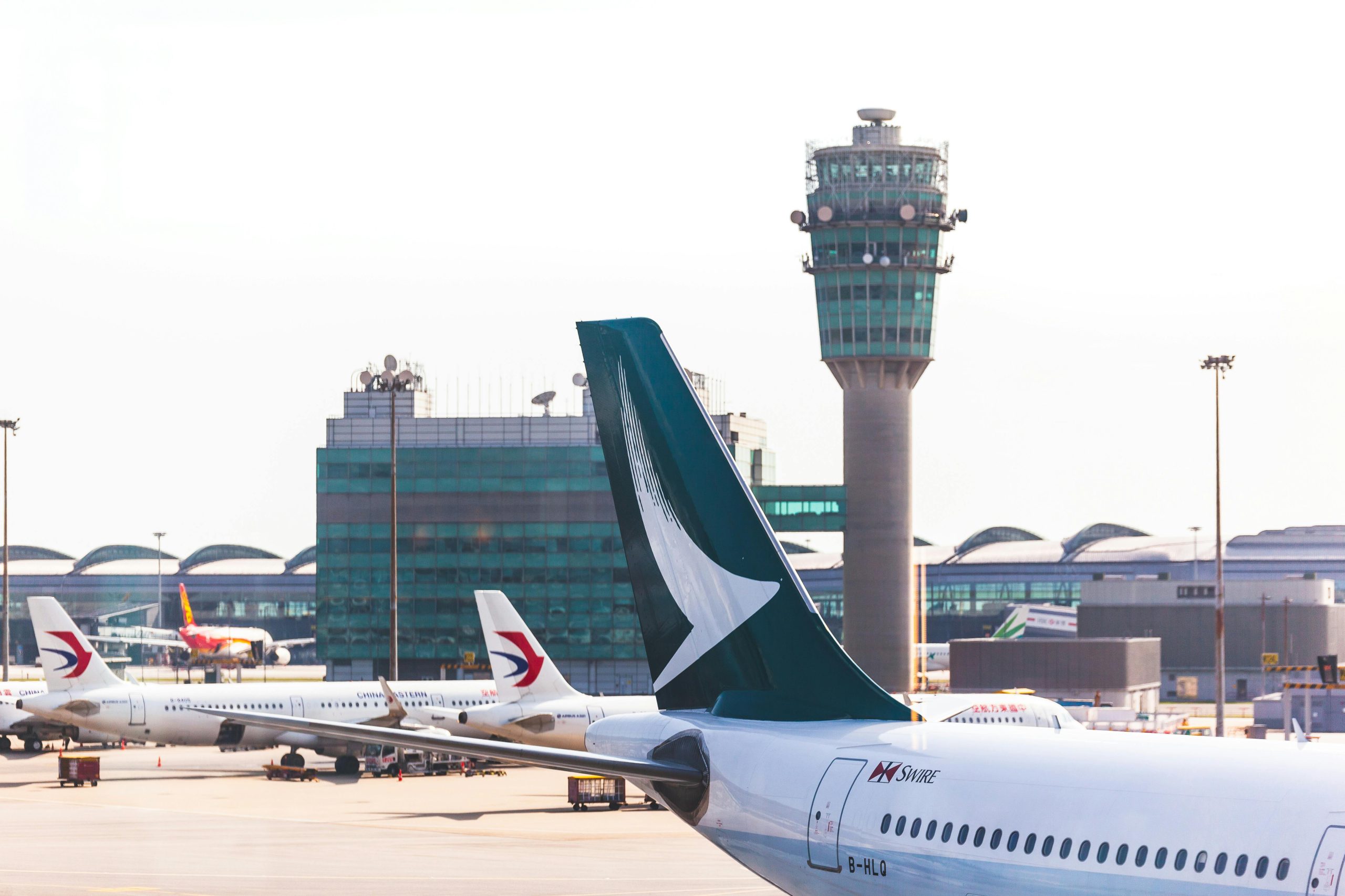 Airplane tailfin and control tower in view at a busy airport terminal.